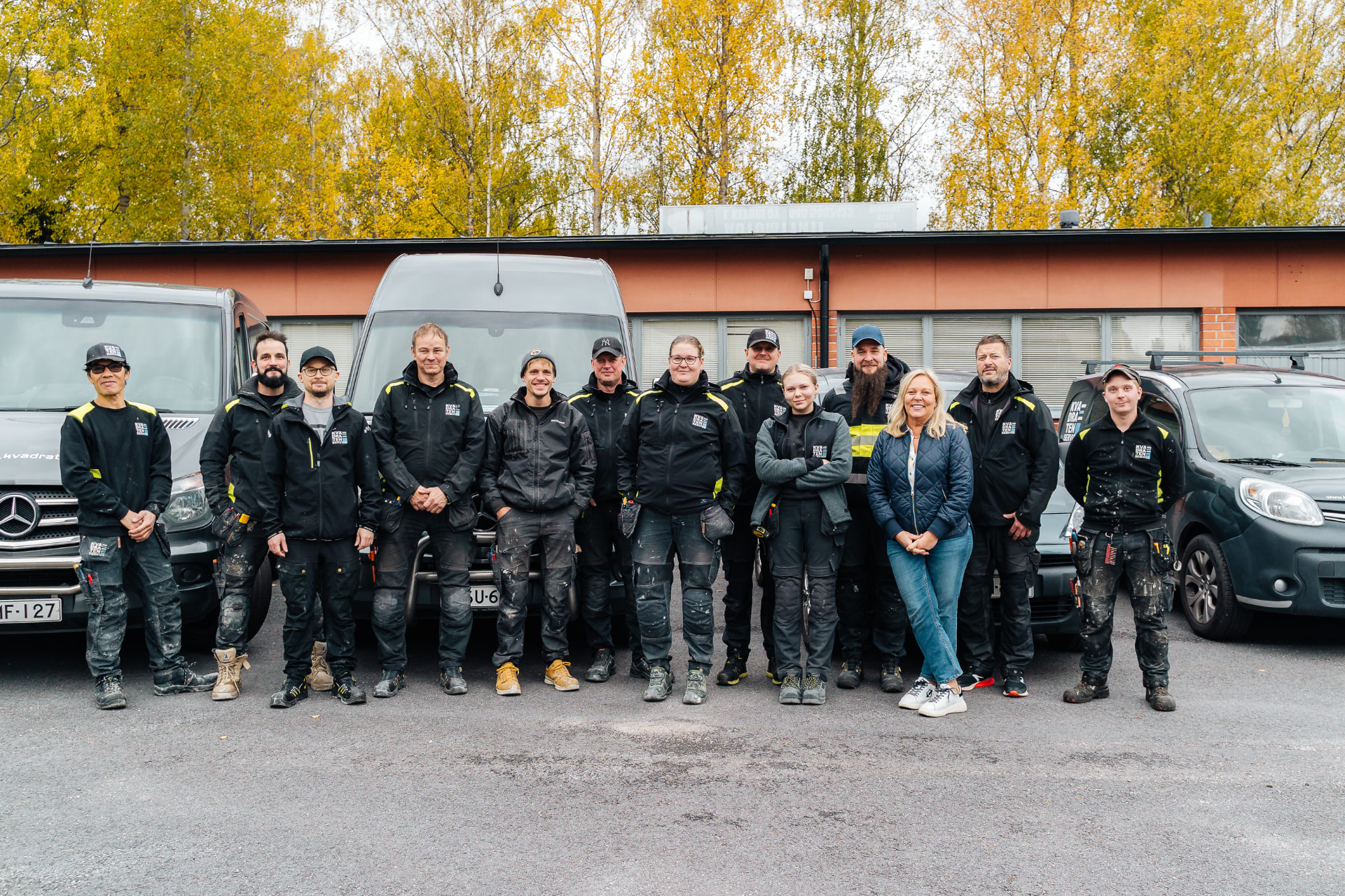 Kvadratenin tiimi yrityksen huoltoautojen edessä